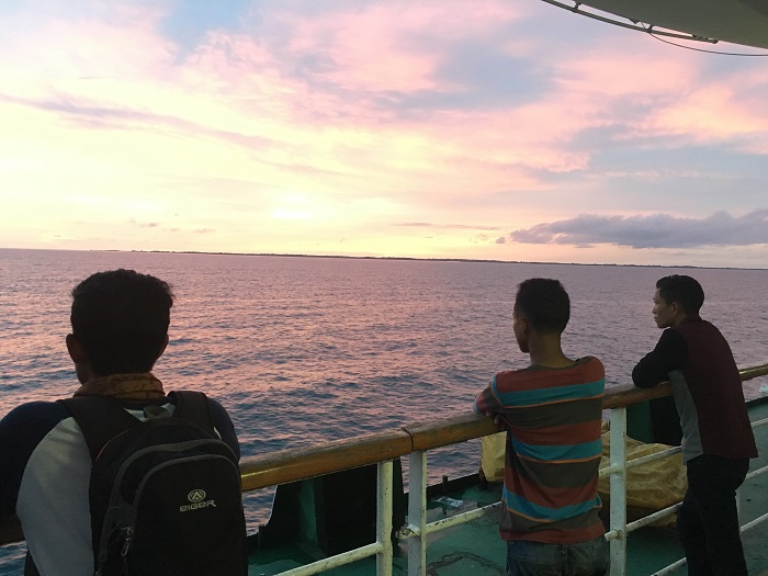 Young men watch the sun set on the way to Makassar / Jessica Clendenning
